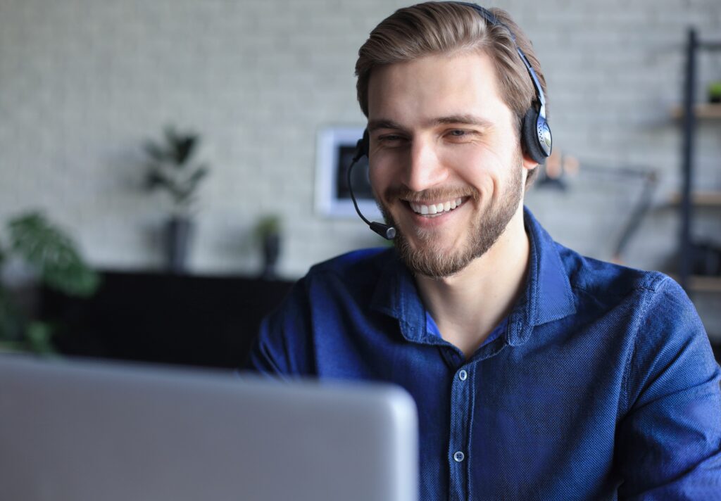 man working on a laptop with headset on